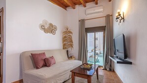 A living room with a sofa, a coffee table, a TV, and a balcony with a view. - Marbella Village  | Appartment with Terrace (Marbella)