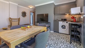 Een compact woongedeelte met een eethoek, een wasmachine, een magnetron en een televisie.