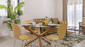 Ein Essbereich mit einem runden Tisch, Stühlen, einer Couch und einer Zimmerpflanze.