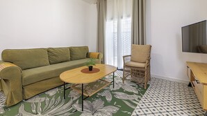 Ein Wohnzimmer mit einer Couch, einem Sessel, einem Couchtisch, einem Fernseher und einem gemusterten Teppich.
