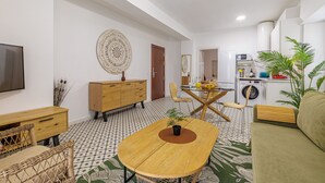 Ein modernes Wohnzimmer mit Esstisch, Sofa und Küchenzeile.