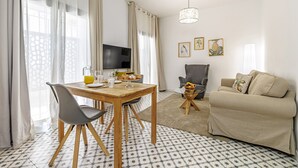 A living room with a sofa, a TV, a dining table with chairs, and a patterned floor. - Casa Castillo | Ground Floor Unit (Marbella)