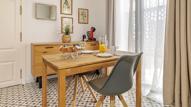 A dining area with a wooden table, chairs, a fruit basket, and a coffee machine. - Casa Castillo | Ground Floor Unit (Marbella)