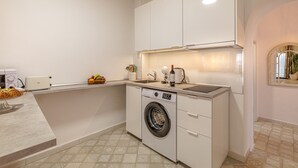 Cocina compacta con lavadora, tostadora y encimera con frutas.