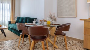 Un rincón de comedor con una mesa dispuesta para dos, un sofá verde y un suelo estampado.