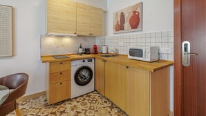 Cocina compacta con armarios de madera, lavadora, microondas y lavabo.