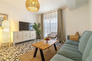 A living room with a sofa, a coffee table, a television, and a patterned floor.