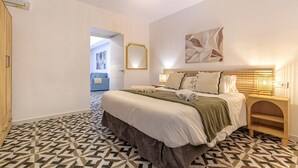 A hotel room with a geometric patterned floor, a bed with a headboard, a bedside table, and a wall-mounted mirror.