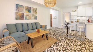 Una sala de estar moderna con un sofá, una mesa de centro y un comedor con taburetes de bar.