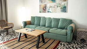 A living room with a green sofa, a wooden coffee table, a patterned rug, and a geometric floor design.