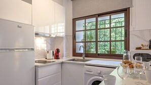 A modern kitchen with a dishwasher, a coffee maker, and a window with a view of greenery.