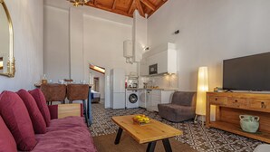 Ein Wohnzimmer mit einer Couch, einem Couchtisch, einem Fernseher und einer Küchenzeile mit Geräten.