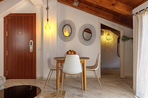 Een eetruimte met een houten tafel, witte stoelen en twee spiegels aan de muur.