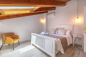 Een slaapkamer met een bed, nachtkastjes, een stoel, houten balken en een airconditioning.