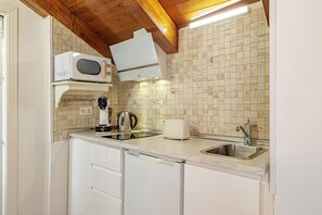 Een kleine keuken met een magnetron, broodrooster, waterkoker en spoelbak.