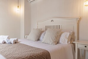 Ein ordentlich bezogenes Bett mit einer gesteppten Decke, zwei strukturierten Kissen und einem Nachttisch mit einer Lampe.