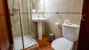 A bathroom with a glass-enclosed shower, a pedestal sink, and a toilet.