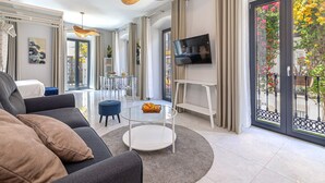 A modern living room with a sofa, coffee table, TV, and a balcony with flowers.