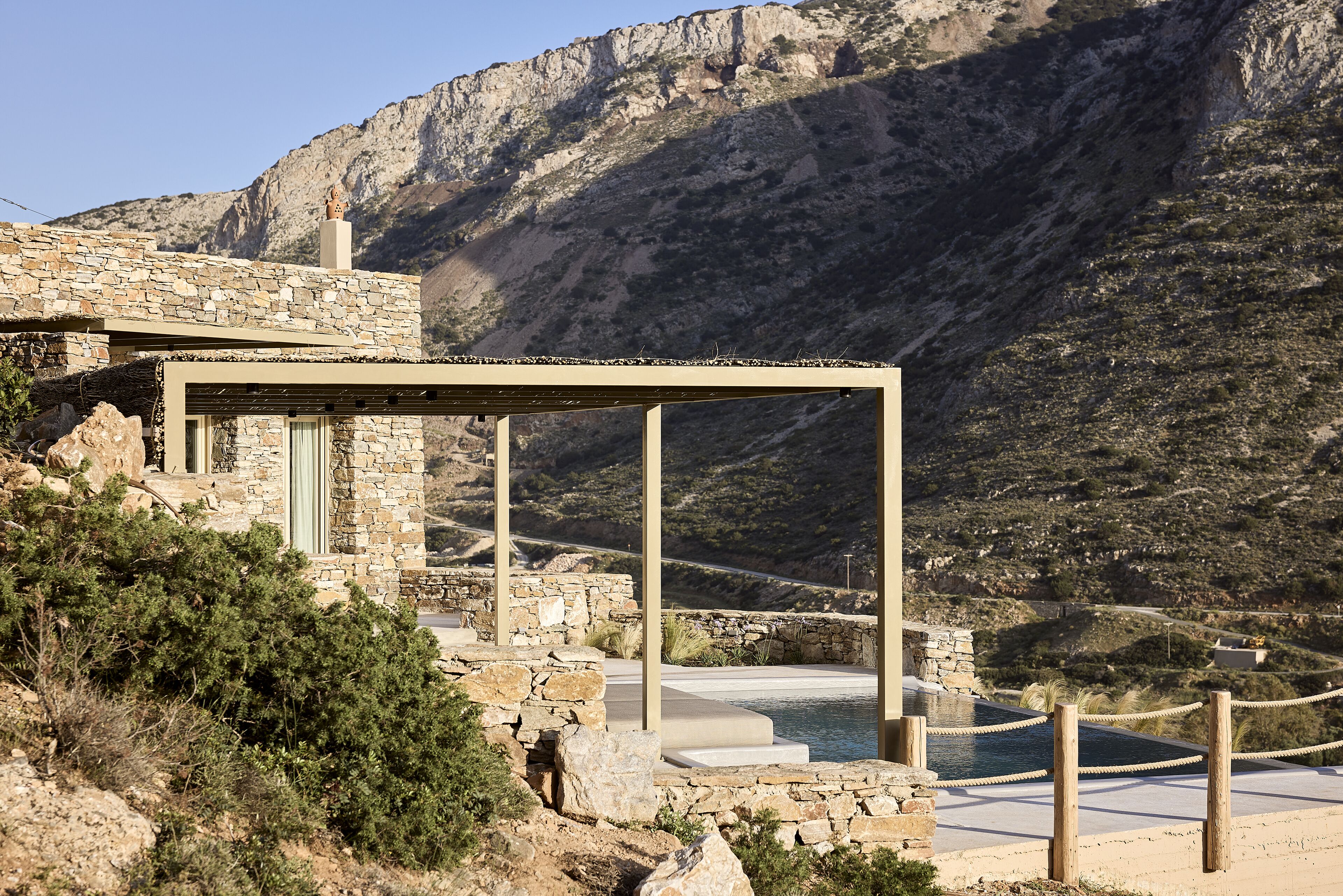 A stone building with a pool and a mountainous backdrop.