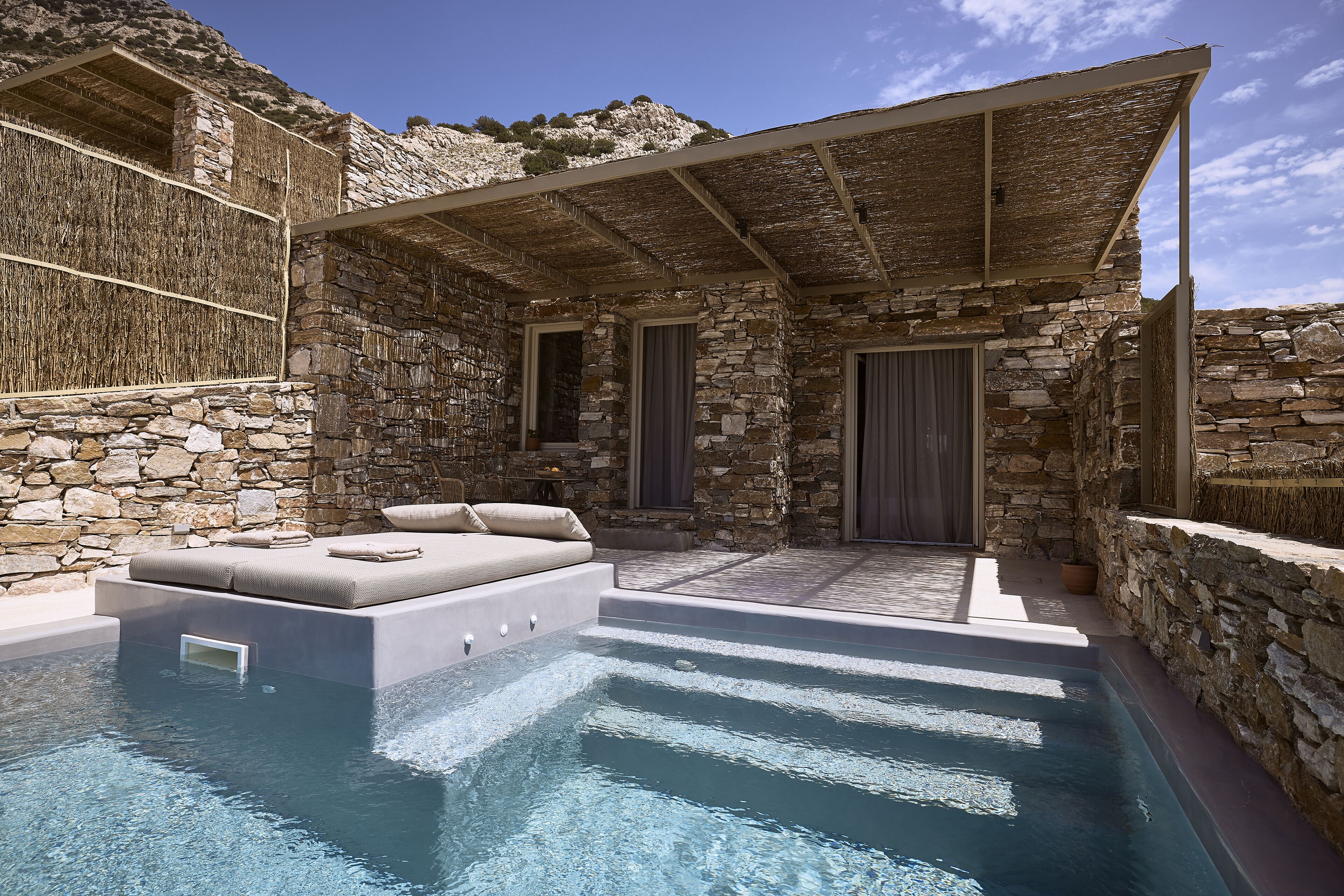 A stone-walled outdoor pool area with a built-in seating area and a covered patio.