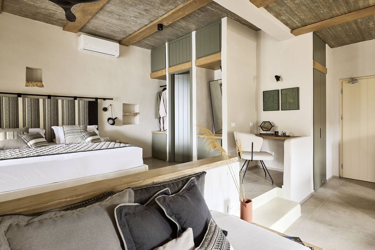 Un dormitorio con una cama grande, un escritorio y una silla. Se ve una ventana con vistas al exterior.