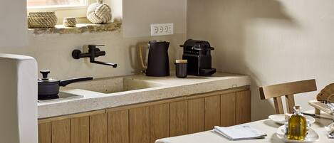 A kitchen with wooden cabinets, a sink, a coffee maker, and a window with a view of greenery.