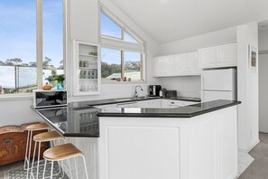 A modern kitchen with white cabinetry, a black countertop, and a large window.