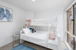 Ein Schlafzimmer mit Etagenbett, einem kleinen runden Tisch und einem blau gemusterten Teppich.