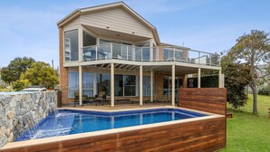 Ein zweistöckiges Haus mit Swimmingpool, überdachter Terrasse und Blick auf die Umgebung.