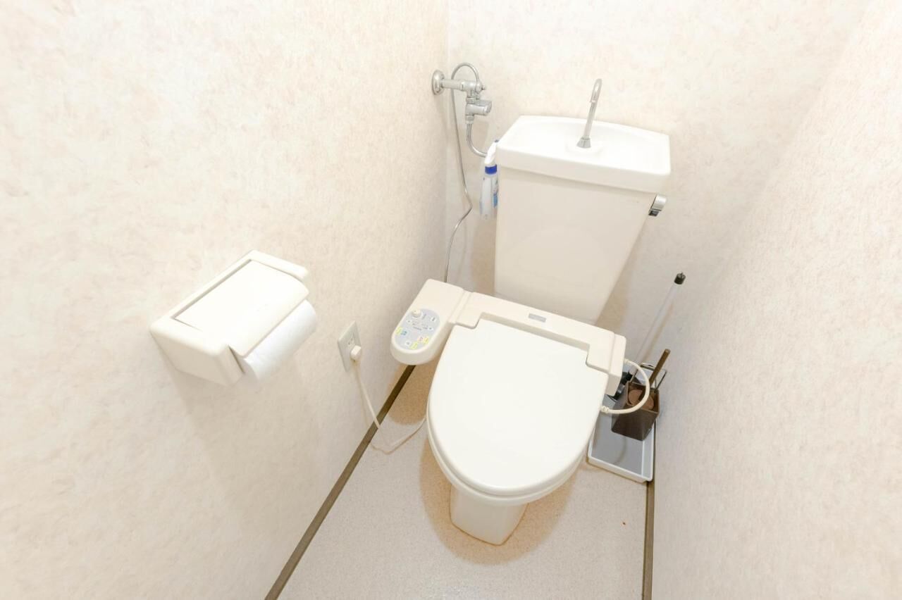 A small, compact bathroom with a toilet, a bidet, and a toilet paper holder.