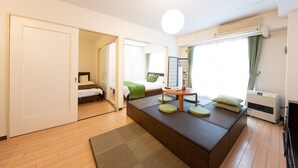 Une chambre d’hôtel moderne avec un grand lit, un coin salon avec des coussins, une petite table et une fenêtre avec des rideaux.