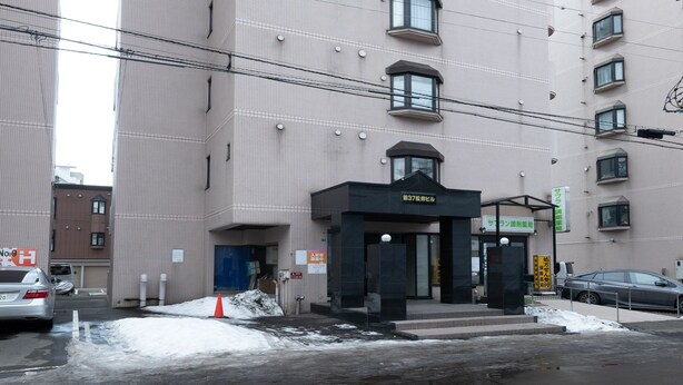 Un immeuble à plusieurs étages, doté d’une série de fenêtres et d’un petit espace d’entrée.