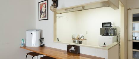 A compact kitchen with a wooden countertop, two bar stools, a refrigerator, a microwave, and a sink.
