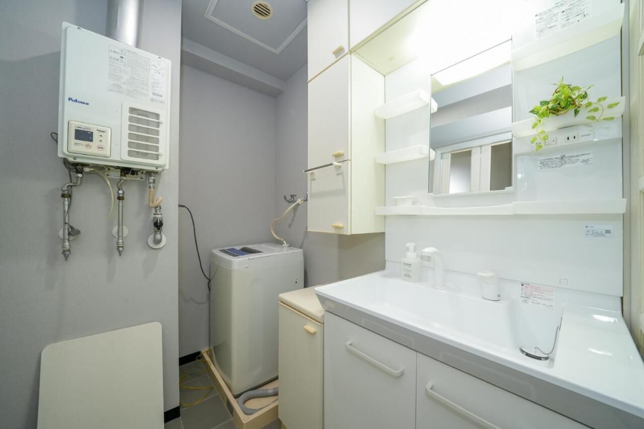 A modern bathroom with a built-in heater, a sink with a mirror, and a small plant on the counter.