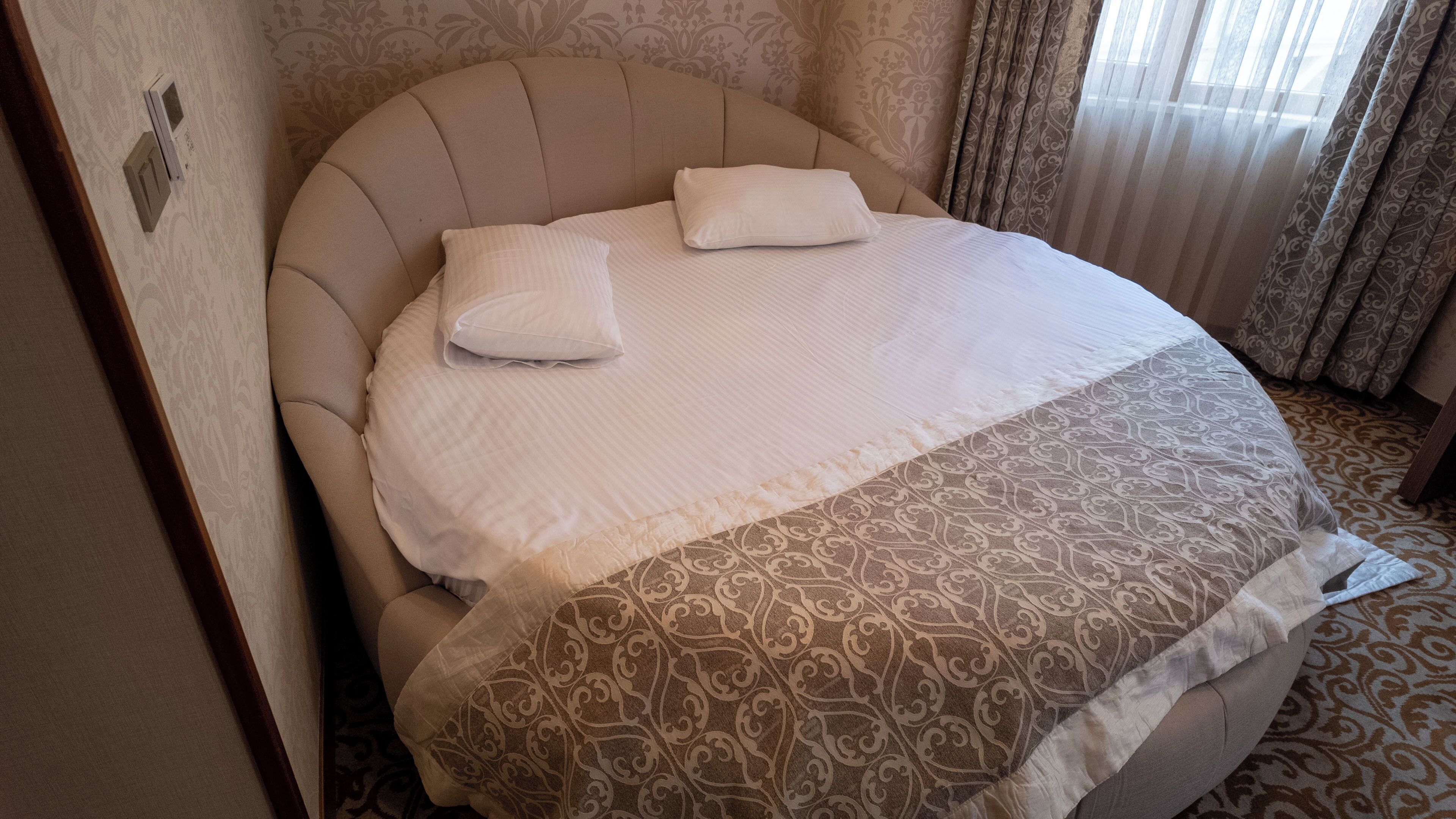 Uma cama com cabeceira, duas almofadas e um cobreleito estampado.