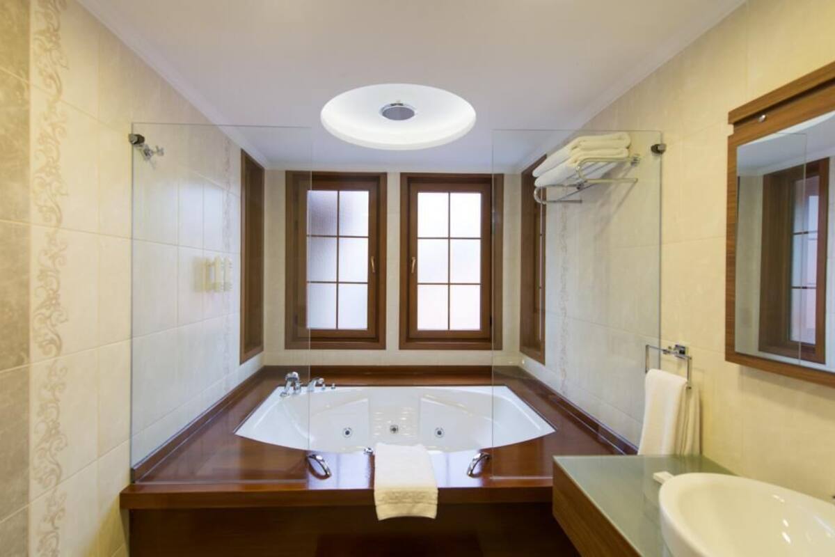 A spacious bathroom with a large bathtub, a separate sink, and a mirror.