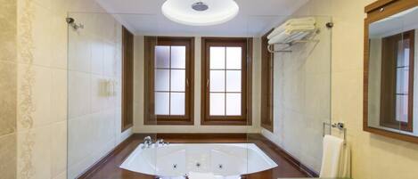 Un baño amplio con una bañera grande, un lavamanos independiente y un espejo.
