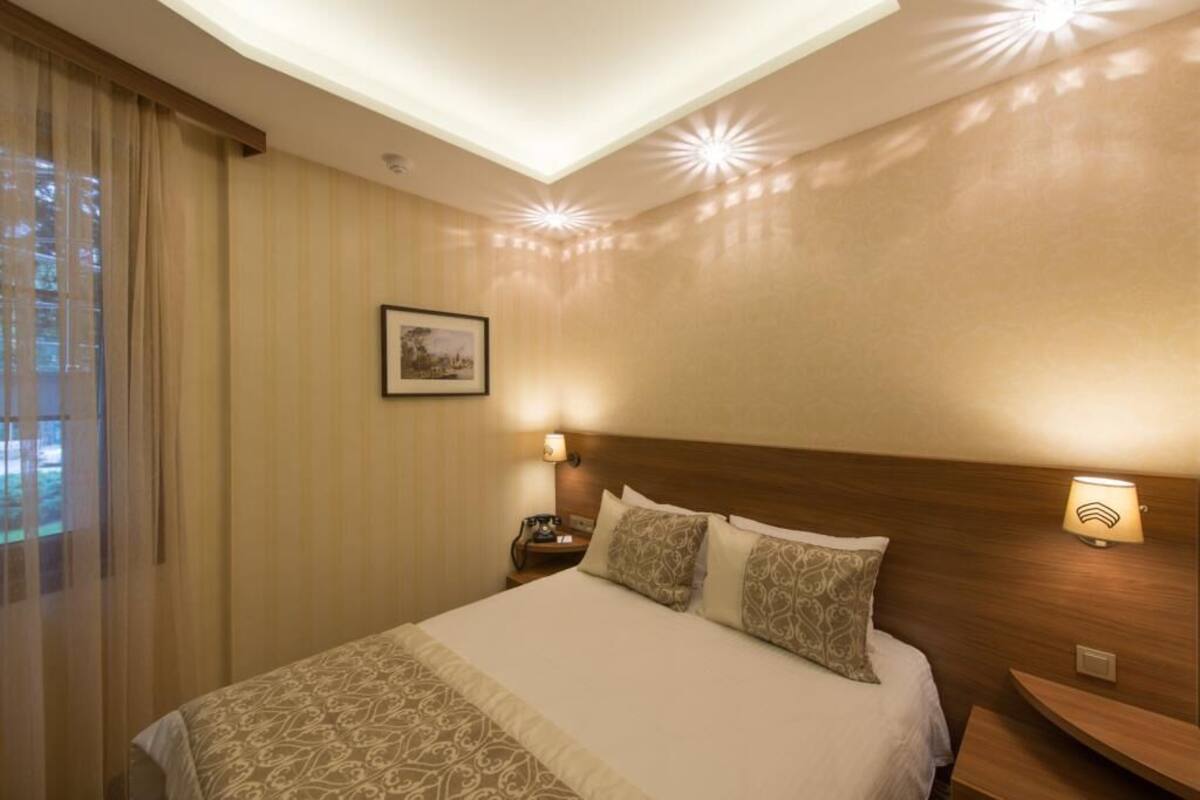 A hotel room with a large bed, two bedside lamps, a nightstand, and a framed picture on the wall.