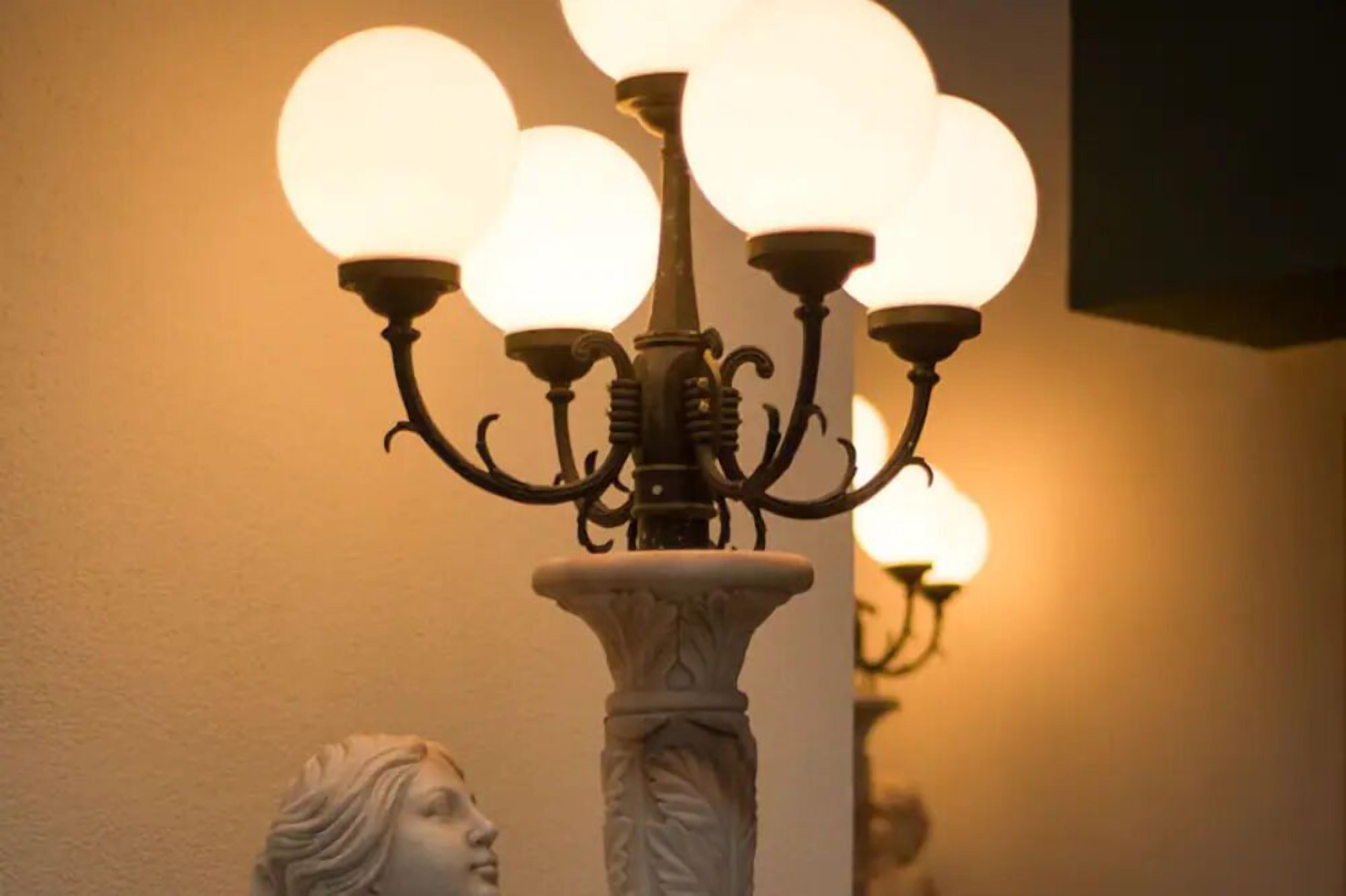 Un candelabro con múltiples bombillas esféricas y una base blanca tipo pedestal.