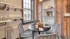 Un coin repas avec une table ronde, des chaises en osier et un mur en briques.