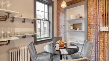 Un coin repas avec une table ronde, des chaises en osier et un mur en briques.
