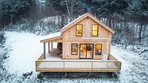 A wooden cabin with a deck, large windows, and a fireplace.
