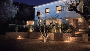 Uma casa moderna com fachada de pedra, várias janelas e uma entrada bem iluminada.