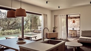 Cozinha moderna com uma ilha grande, área de jantar com vista para a piscina e um espaço de estar acolhedor com parede de pedra.