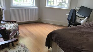 Ein Schlafzimmer mit einem Bett, einem Schreibtisch mit Computer, einem Stuhl und einer Heizung.