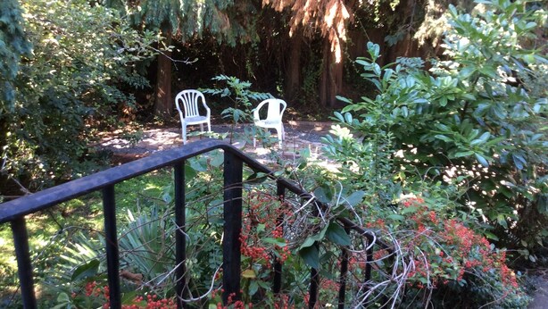 Ein Garten mit zwei weißen Kunststoffstühlen und einem Metallgeländer.