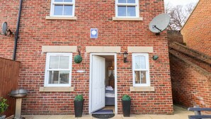 A two-story brick house with a front door, two windows on the ground floor, and a satellite dish on the right. - Stoker's Rest (Whitby)