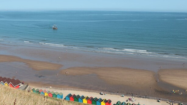 A beach with colorful beach huts and a clear view of the sea. - Stoker's Rest (Whitby)