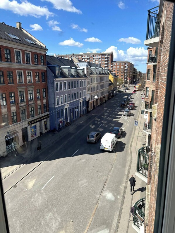 A street view with buildings, a clear sky, and a few cars.