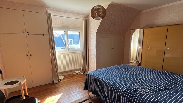 Une chambre à coucher comprenant un lit, un bureau, une chaise, une fenêtre et un ventilateur de plafond.